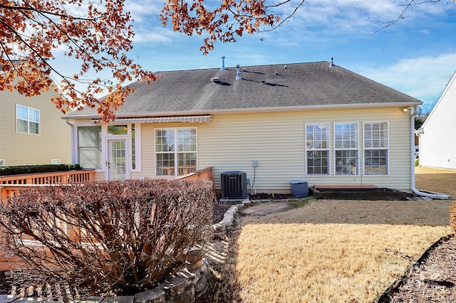 back of property with central AC unit and a lawn