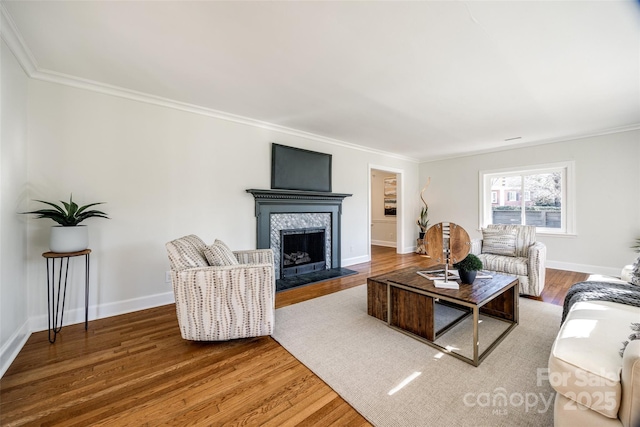 living room featuring hardwood / wood-style flooring, ornamental molding, and a tiled fireplace