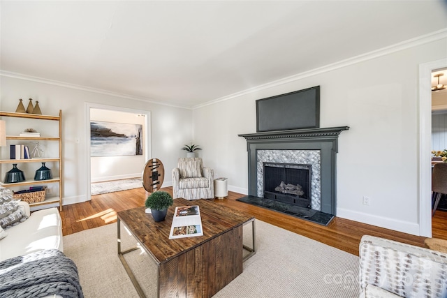 living room with light wood-type flooring, ornamental molding, and a tiled fireplace