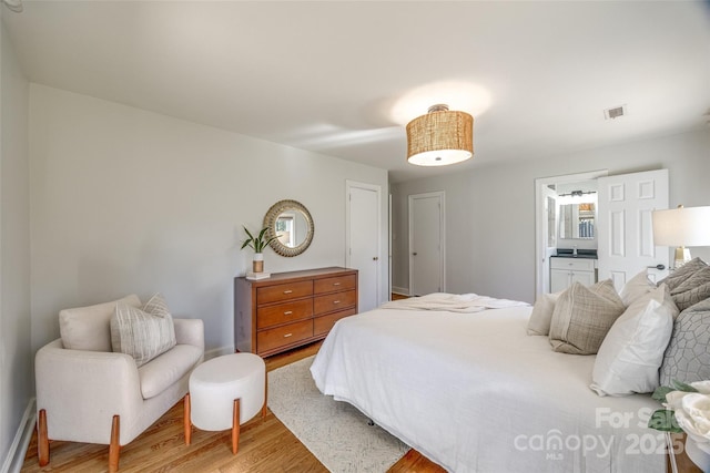 bedroom featuring ensuite bath and light wood-type flooring