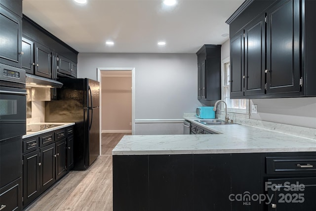 kitchen featuring sink, kitchen peninsula, light hardwood / wood-style floors, and black appliances