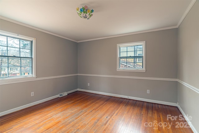 empty room featuring wood-type flooring, a wealth of natural light, and ornamental molding