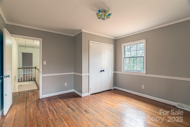 unfurnished bedroom featuring hardwood / wood-style flooring, a closet, and ornamental molding