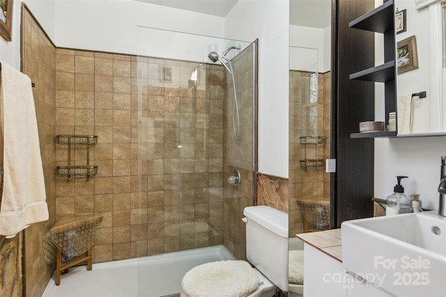 bathroom with a tile shower, sink, and toilet