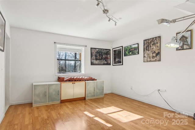 unfurnished bedroom with track lighting and light hardwood / wood-style flooring