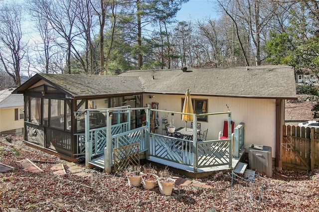 rear view of house with central air condition unit and a sunroom