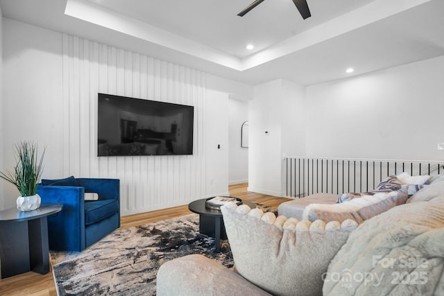 living room featuring ceiling fan, hardwood / wood-style flooring, and a raised ceiling