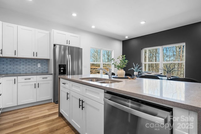 kitchen featuring white cabinetry, stainless steel appliances, tasteful backsplash, light stone countertops, and sink