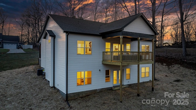 back house at dusk with a balcony and central air condition unit