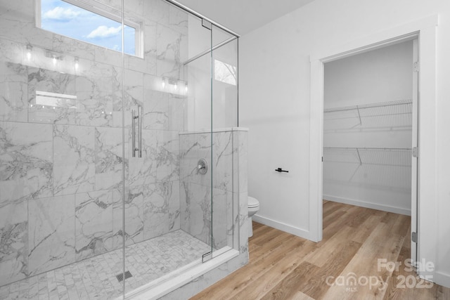 bathroom featuring wood-type flooring, toilet, and a shower with door