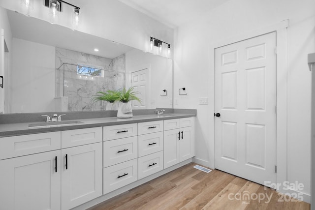 bathroom with a shower with shower door, wood-type flooring, and vanity