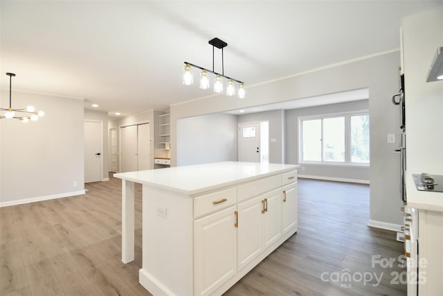 kitchen with light wood-type flooring, a center island, white cabinetry, and hanging light fixtures