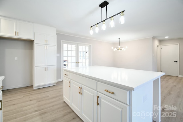 kitchen with pendant lighting, a kitchen island, white cabinets, and light hardwood / wood-style floors