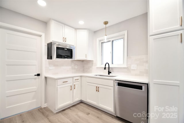 kitchen with white cabinetry, sink, backsplash, decorative light fixtures, and appliances with stainless steel finishes