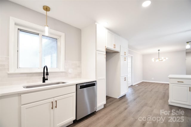 kitchen with tasteful backsplash, white cabinets, sink, pendant lighting, and dishwasher