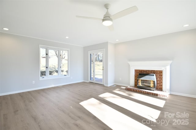 unfurnished living room featuring ceiling fan, light hardwood / wood-style floors, crown molding, and a fireplace