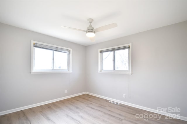 spare room with ceiling fan, plenty of natural light, and light wood-type flooring