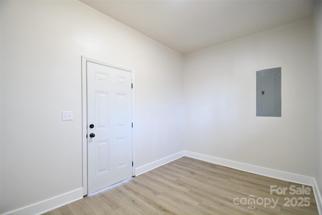 spare room with electric panel and light wood-type flooring