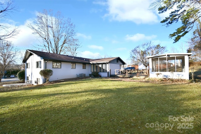 rear view of property with a sunroom, a yard, and central AC