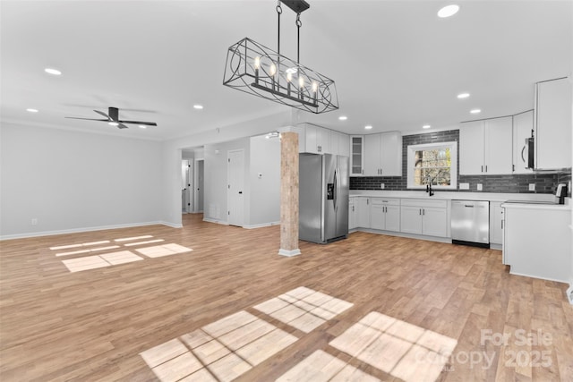 kitchen with stainless steel appliances, ceiling fan, sink, pendant lighting, and white cabinetry