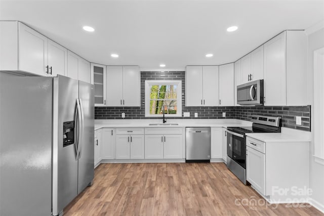 kitchen with decorative backsplash, white cabinetry, sink, and appliances with stainless steel finishes