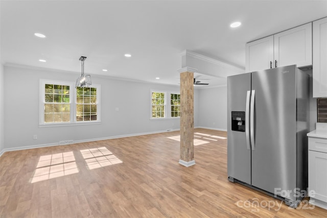 kitchen with decorative columns, stainless steel fridge, white cabinetry, and ornamental molding