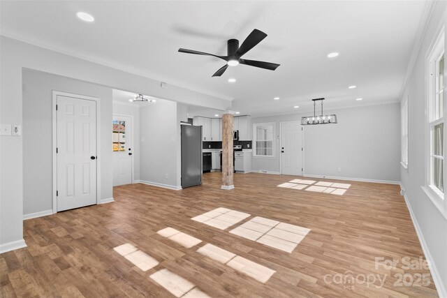 unfurnished living room with ceiling fan, crown molding, and light wood-type flooring