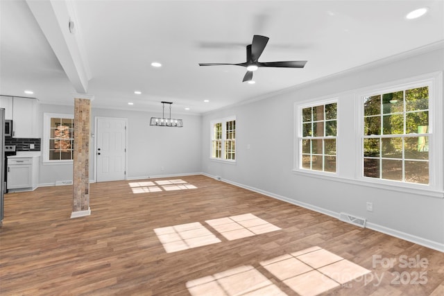 unfurnished living room with decorative columns, ceiling fan, plenty of natural light, and light wood-type flooring