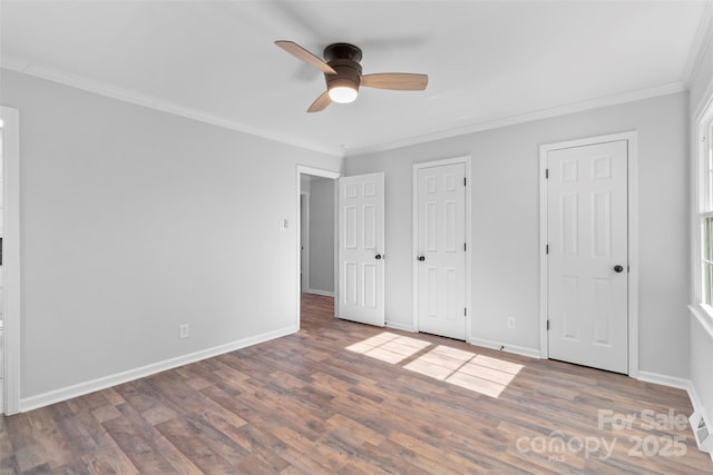 unfurnished bedroom featuring two closets, ceiling fan, hardwood / wood-style flooring, and ornamental molding