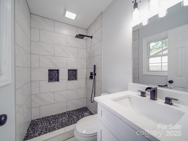 bathroom with vanity, toilet, and tiled shower