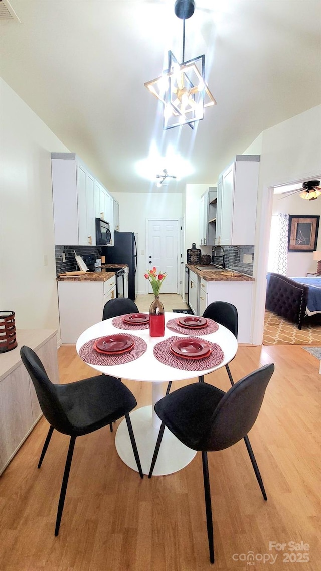 dining space with light wood-type flooring, sink, and an inviting chandelier