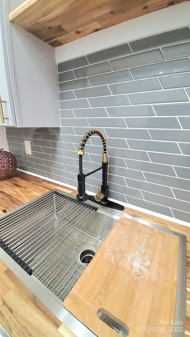 interior details with decorative backsplash, sink, and butcher block countertops