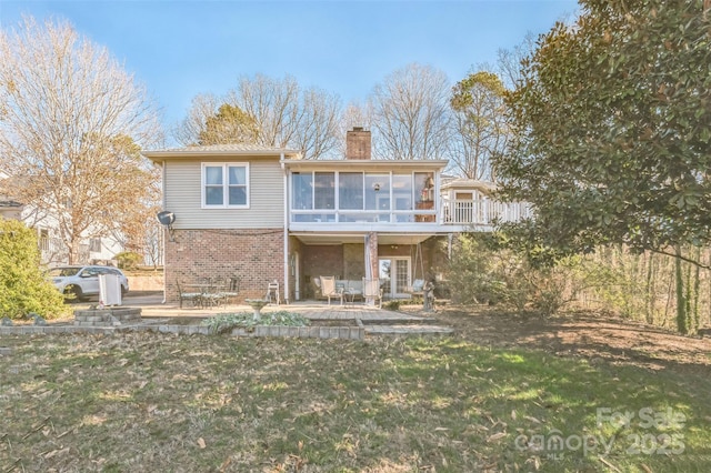 rear view of property with a sunroom, a patio area, and a lawn