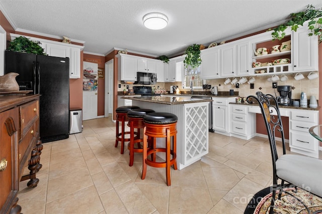 124 Muirfield Dr, Kings Mountain, NC 28086 - kitchen featuring black appliances, dark countertops, white cabinetry, a kitchen island, and a kitchen bar