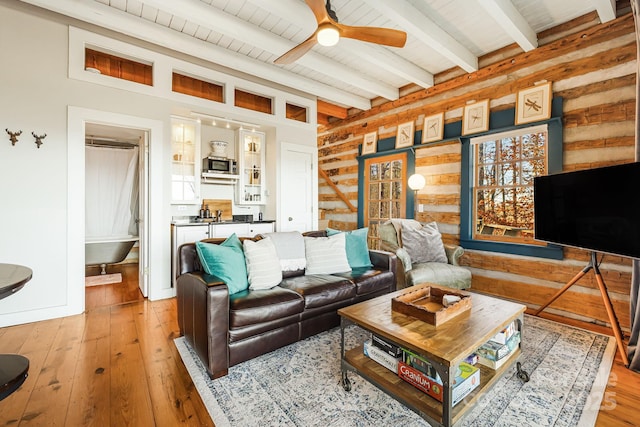 living room with wood walls, ceiling fan, hardwood / wood-style flooring, and beamed ceiling