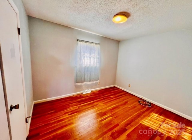 spare room with hardwood / wood-style floors and a textured ceiling