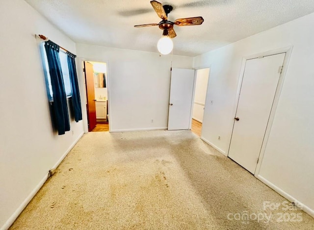 unfurnished bedroom featuring ceiling fan, light colored carpet, a textured ceiling, and connected bathroom