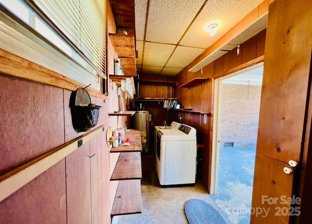 laundry room with washer and dryer, brick wall, gas water heater, and wooden walls