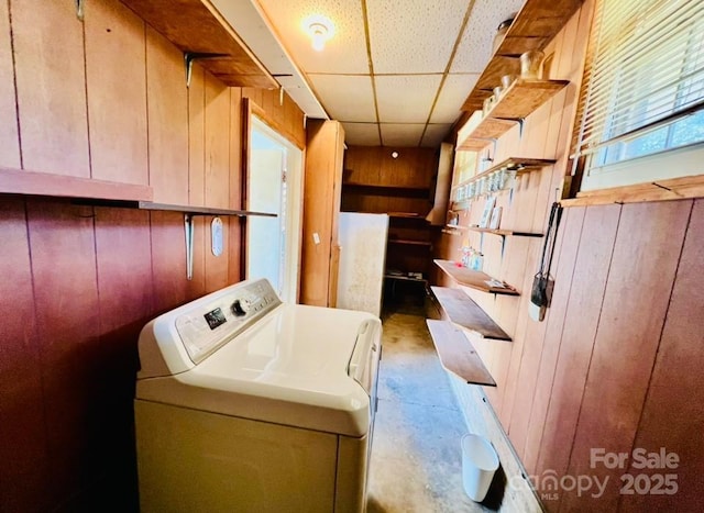 washroom with wood walls and washer / dryer