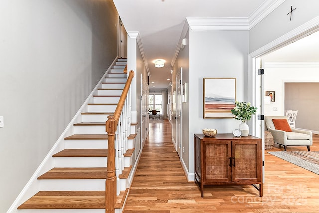 staircase with ornamental molding and hardwood / wood-style floors