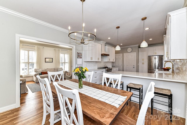 dining space featuring ornamental molding, sink, a notable chandelier, and dark hardwood / wood-style flooring