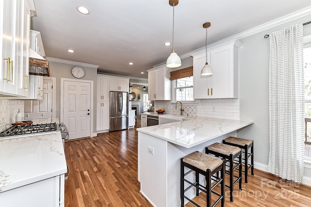 kitchen featuring pendant lighting, stainless steel refrigerator, sink, white cabinets, and light stone counters