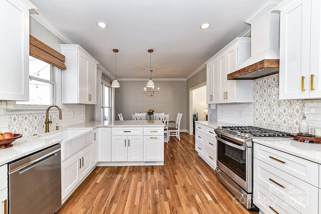 kitchen featuring pendant lighting, white cabinetry, stainless steel appliances, and premium range hood