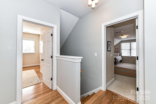 hall with lofted ceiling and light hardwood / wood-style flooring