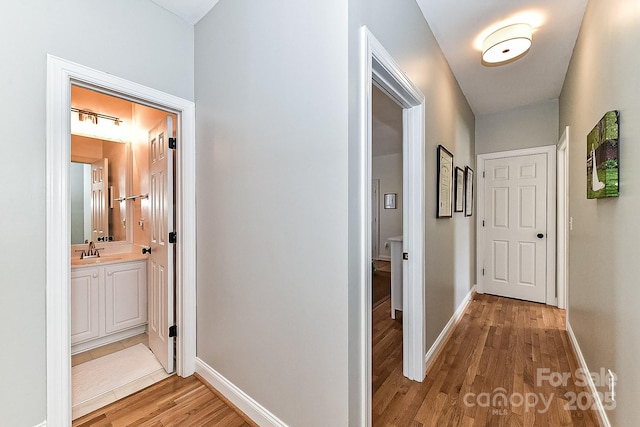 hallway with sink and light hardwood / wood-style floors