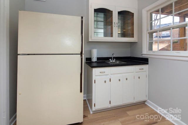 kitchen featuring white refrigerator, sink, light hardwood / wood-style flooring, and white cabinets