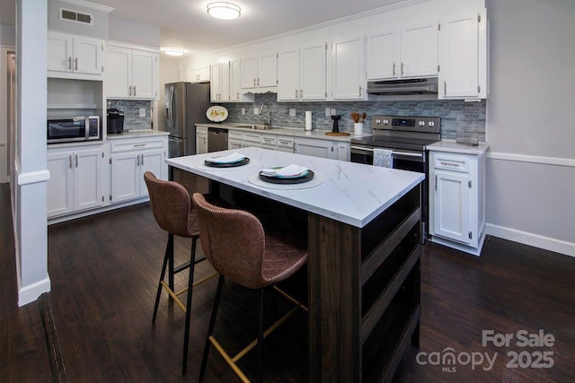 kitchen with stainless steel appliances, white cabinetry, sink, and decorative backsplash