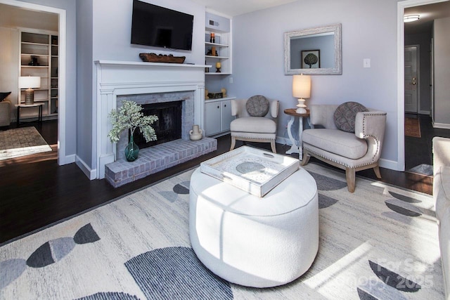 living room with dark wood-type flooring, a fireplace, and built in features