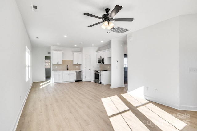 unfurnished living room featuring light hardwood / wood-style floors, ceiling fan, and sink