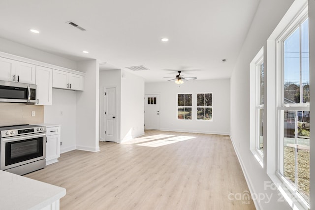 kitchen with ceiling fan, tasteful backsplash, appliances with stainless steel finishes, white cabinets, and light wood-type flooring